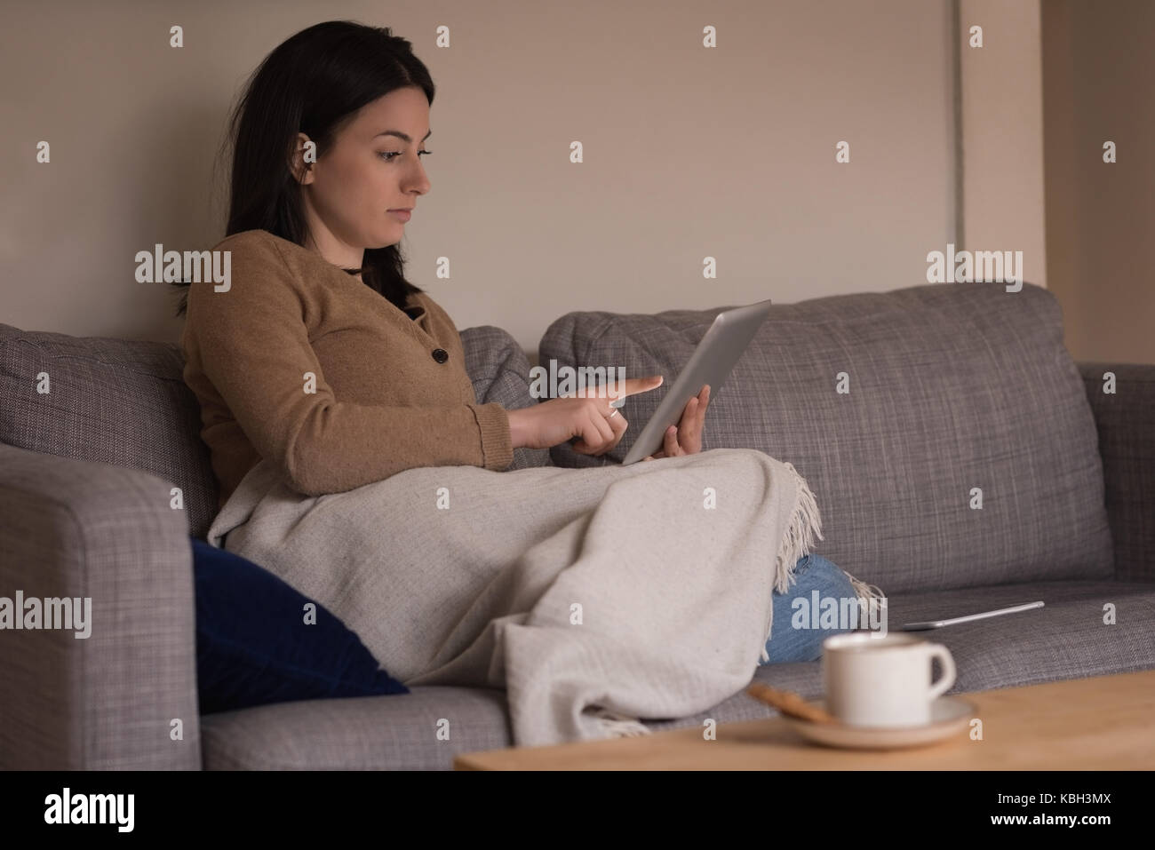 Jeune femme détendue à l'aide de tablet on sofa at home Banque D'Images