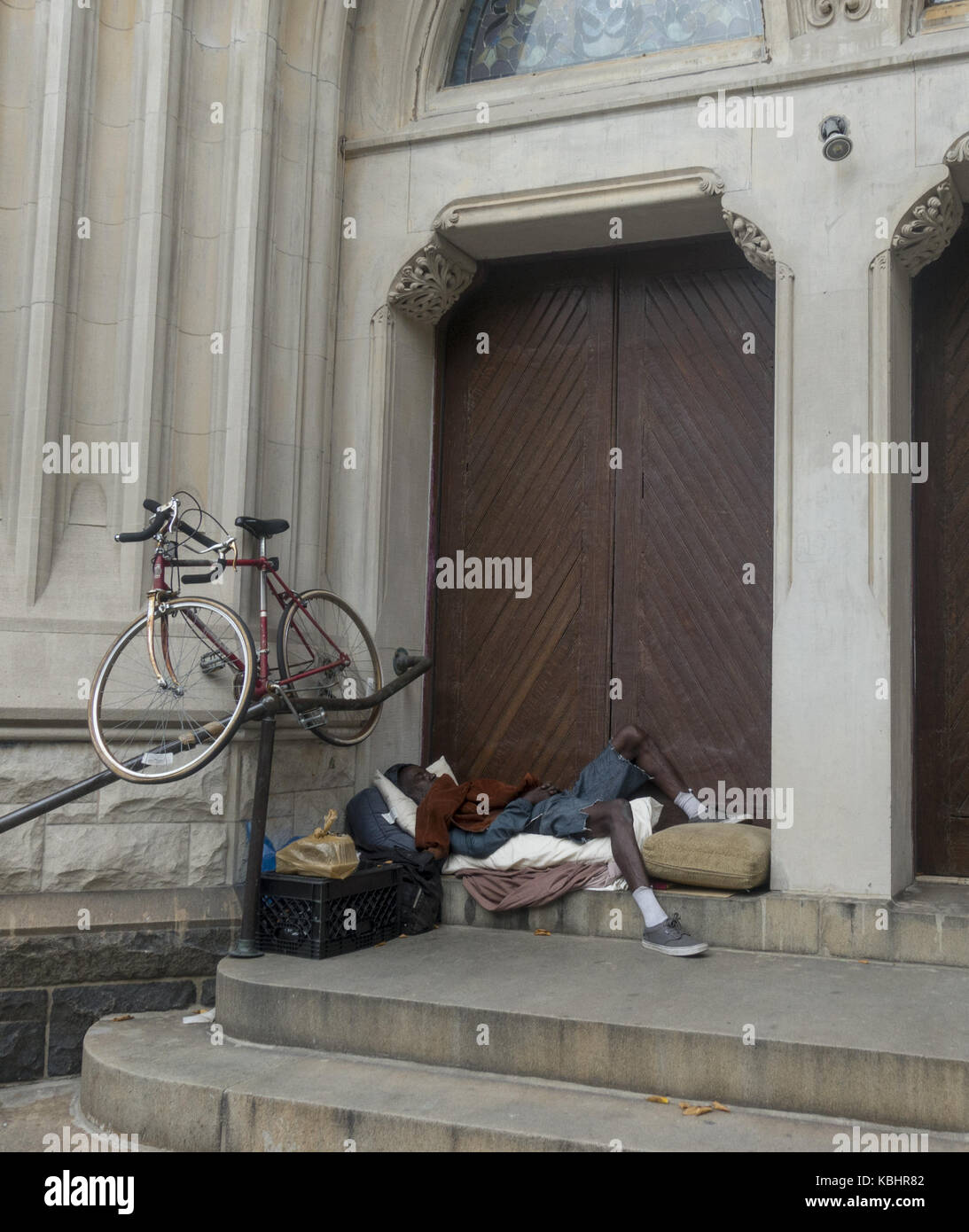 Sans-abri avec son vélo dort à l'entrée d'une église sur la 7e avenue à Park Slope, Brooklyn, New York. Banque D'Images