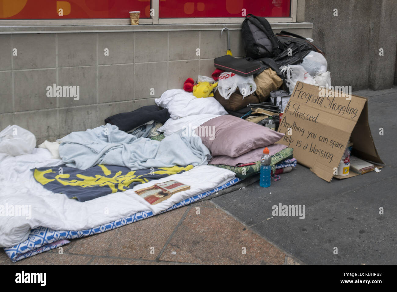 Trottoir lieu de nidification d'une femme sans-abri avec un panneau nous informant qu'elle est enceinte et a vraiment besoin d'aide. midtown Manhattan, New York. Banque D'Images