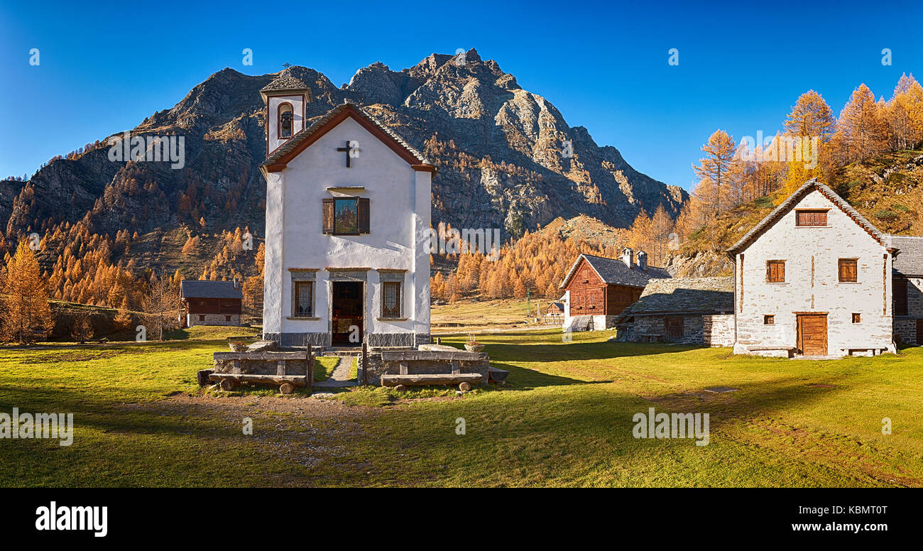 Petite église dans ancien village au coucher du soleil en saison d'automne avec une longue ombre sur l'herbe verte Banque D'Images