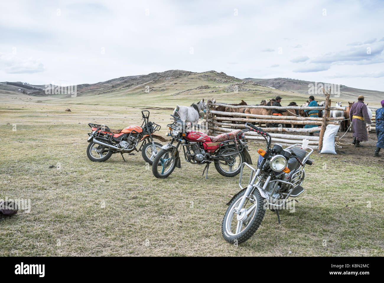 Mongolie - 22 mai 2017 : les motos debout près de corral avec les chevaux dans la prairie à jour nuageux Banque D'Images