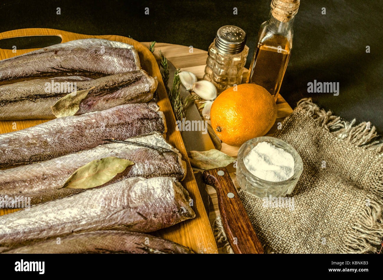 Merlu congelés avec la feuille de laurier sur le plateau en plastique du couteau de cuisine, l'huile d'olive et citron Banque D'Images