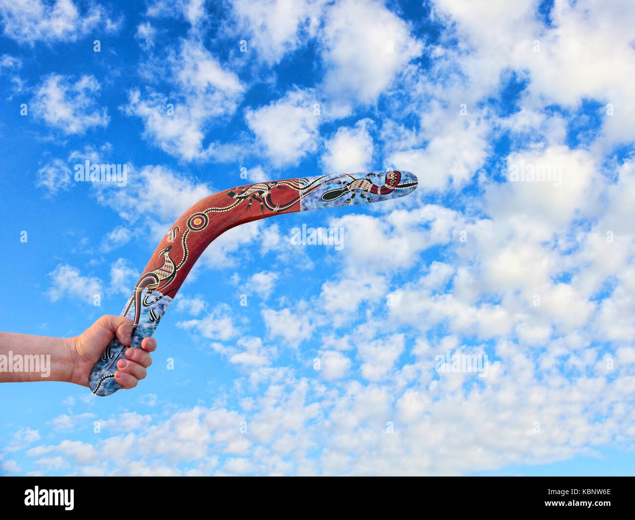 En boomerang australien couleur main libre contre les hommes pris de nuageux ciel bleu. Banque D'Images