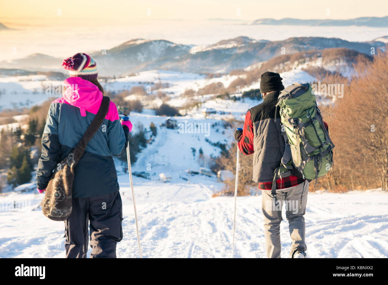 Couple marchant dans la montagne enneigée à l'heure du coucher du soleil romantique Banque D'Images