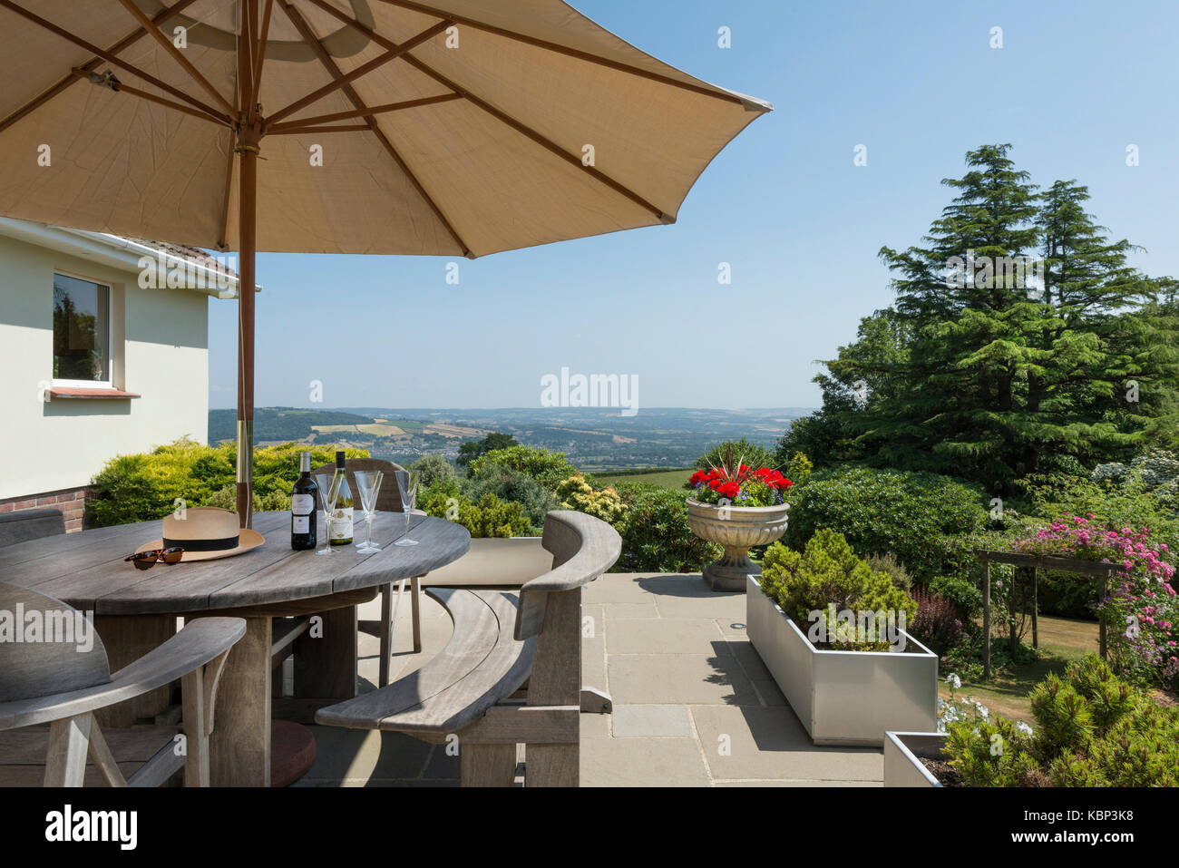 Bouteille de vin et des verres s'asseoir sur une table de jardin en bois contre une vue imprenable sur le Dartmoor dans le devon le long d'une journée d'été Banque D'Images