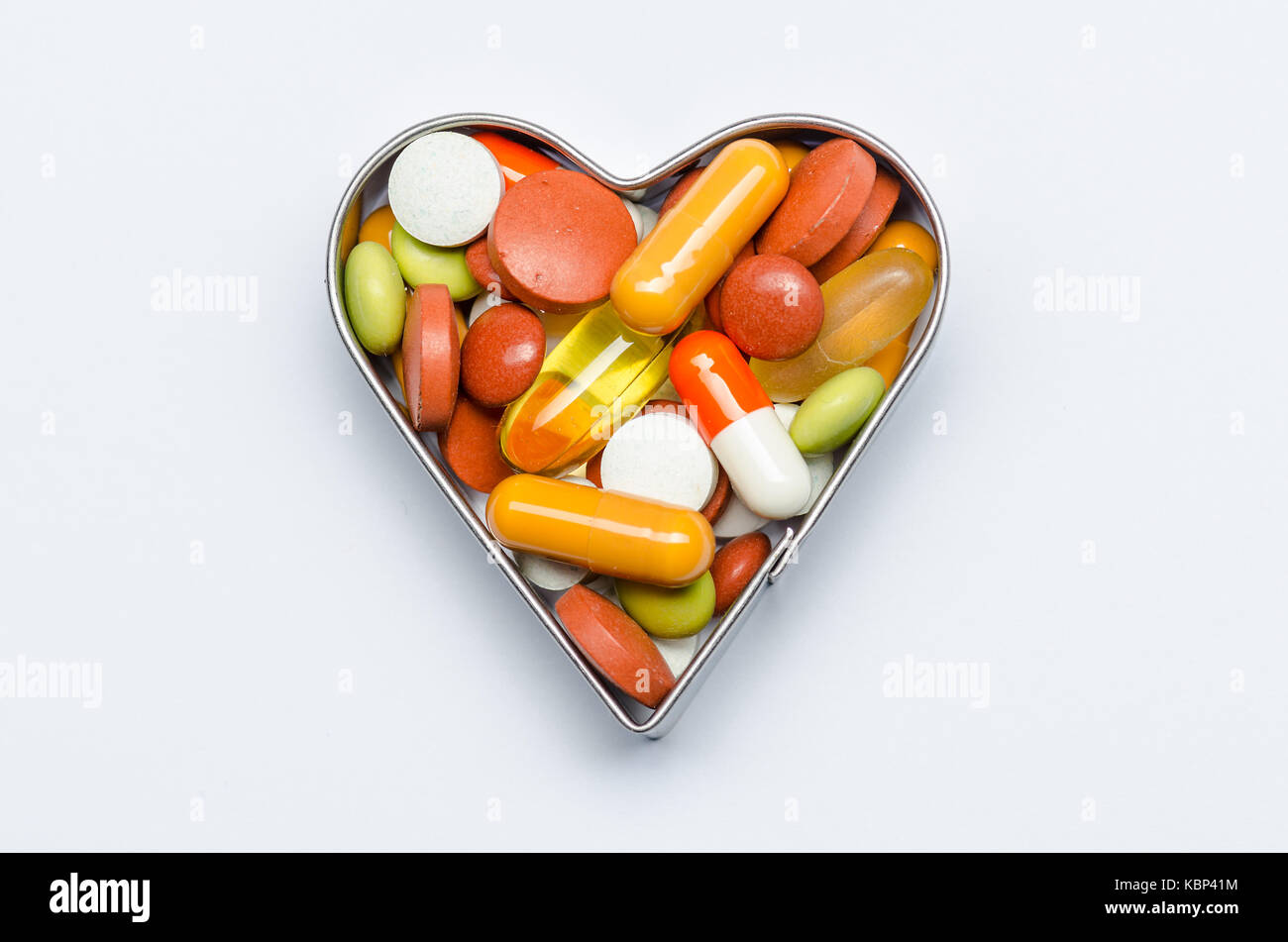 Cordatly en cœur tas de pilules colorées isolé Banque D'Images
