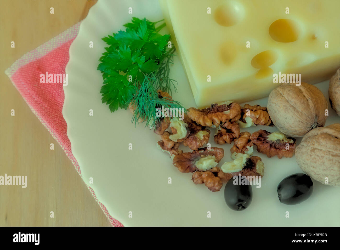 Sur la table sur une plaque blanche pour obtenir le fromage, les noix et les olives. L'effet de la Polaroid. Banque D'Images