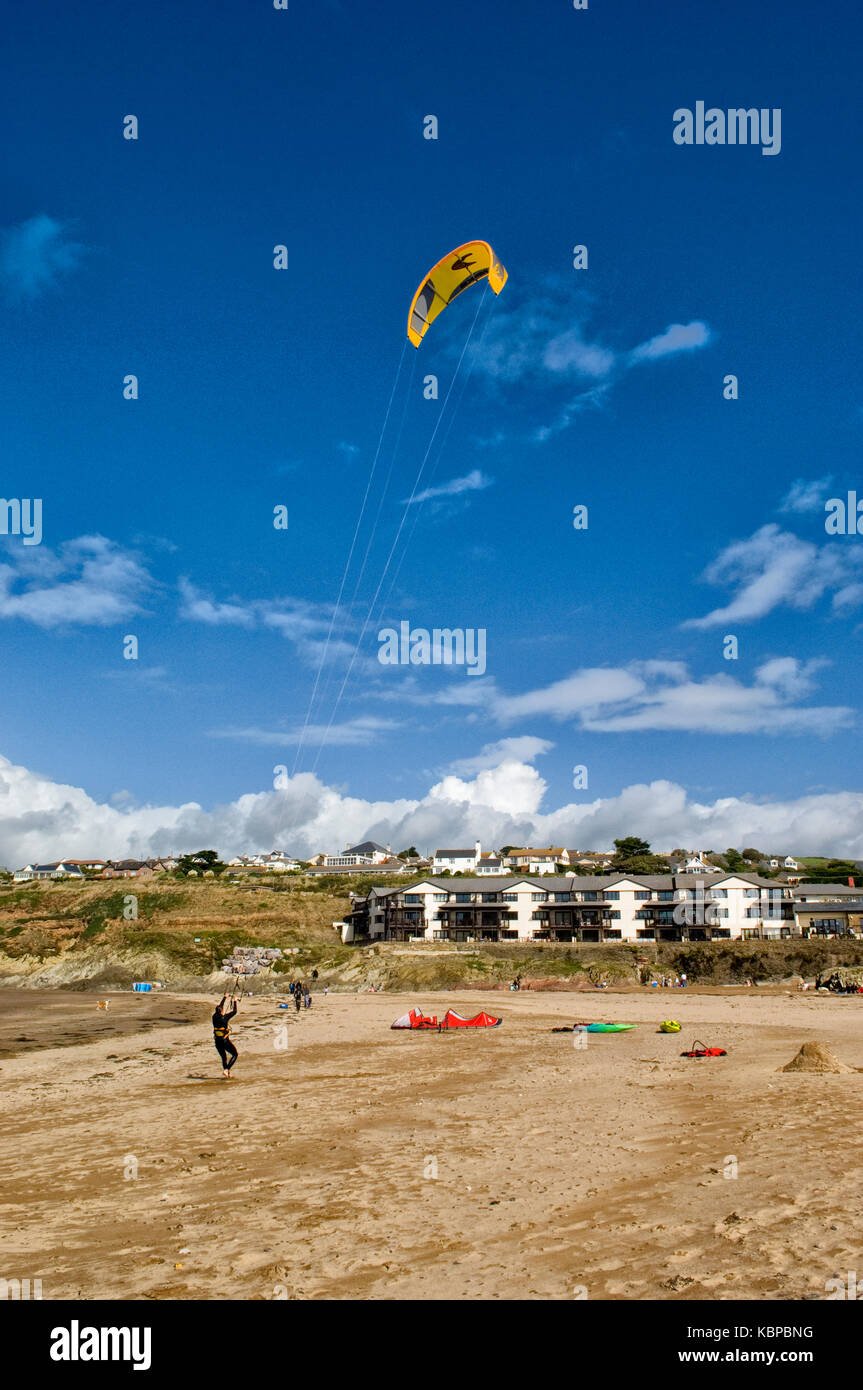 Le kite surfer pratique sur la plage de Bigbury on Sea, Devon avec le cerf-volant jaune en plein vol contre un ciel bleu clair. espace copie, kayaks Banque D'Images