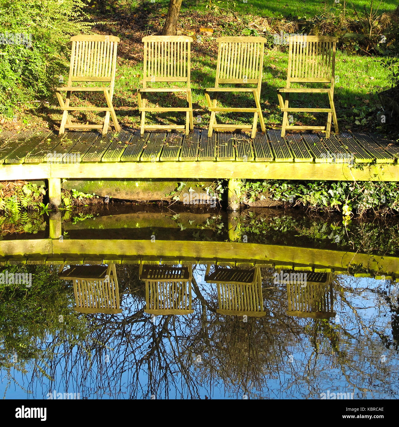 Quatre chaises en bois vides sur une jetée de canal, Monbucshire et Brecon Canal, pays de Galles, Royaume-Uni Banque D'Images