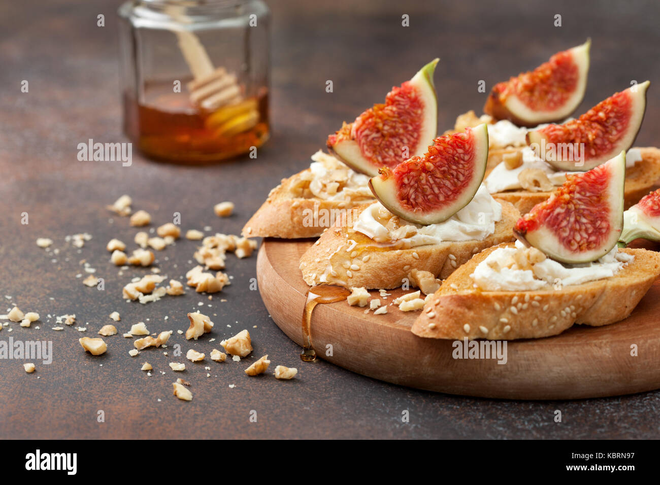 Des sandwichs aux figues, ricotta, miel et noix sur un fond brun Banque D'Images