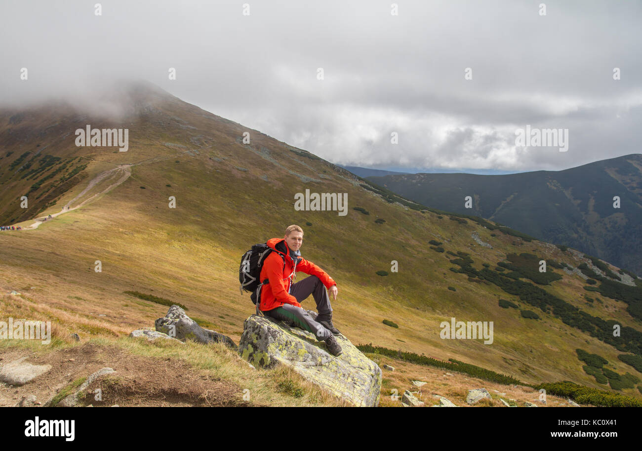 Randonneur assis sur rock builder en montagne Banque D'Images