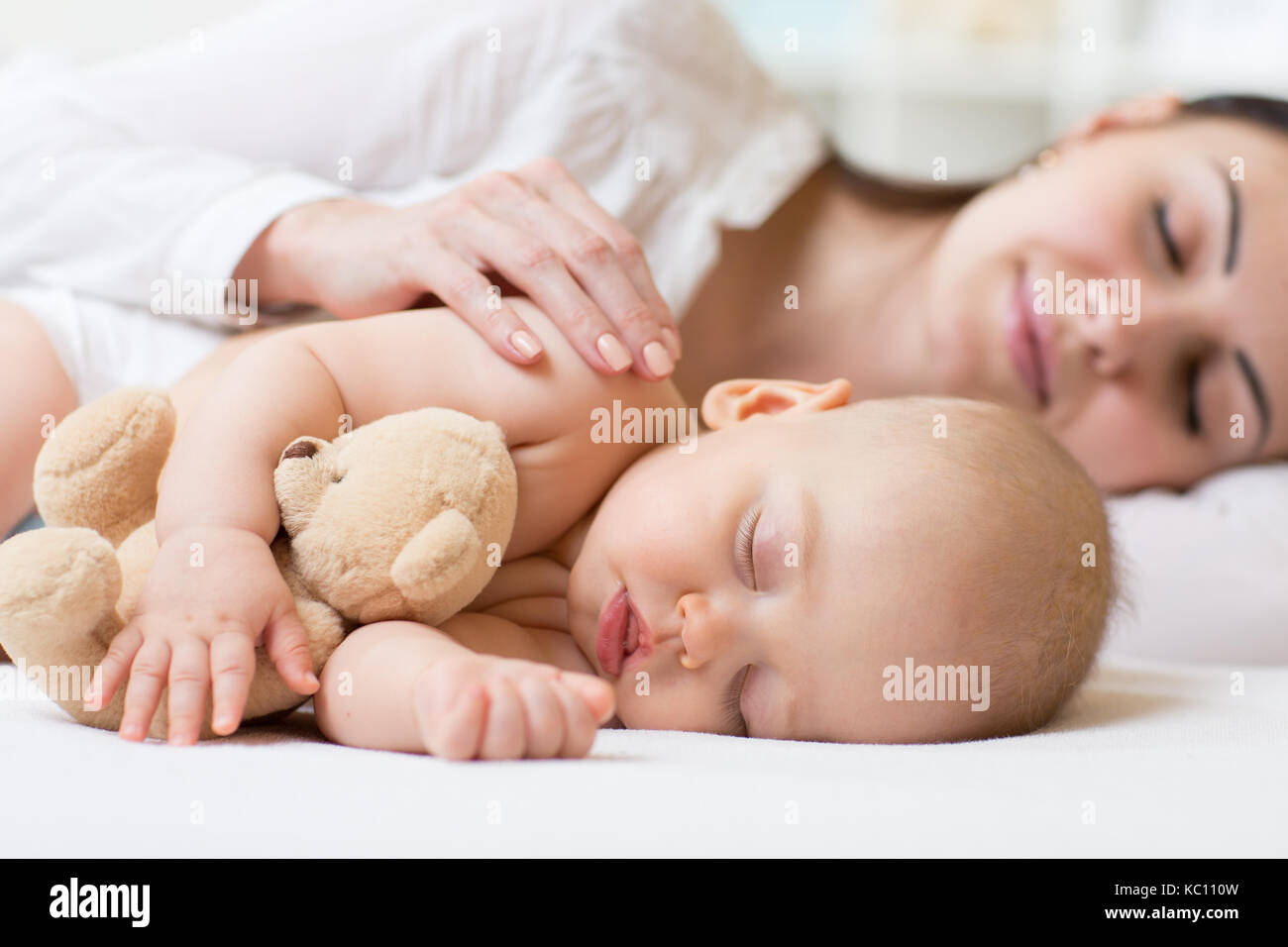 Belle jeune maman et son petit bébé qui dort dans le lit à la maison Banque D'Images