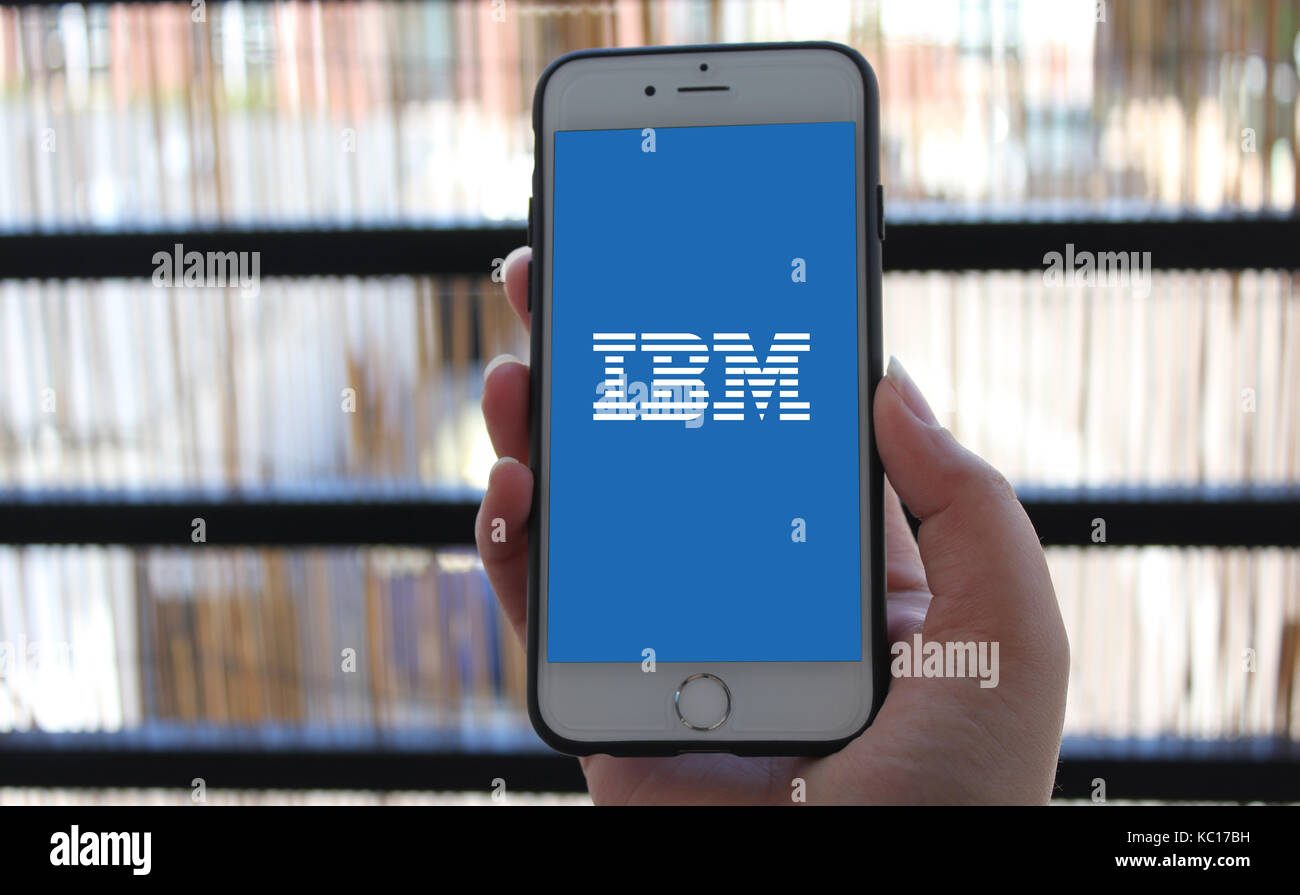 Consumer holding phone avec logo IBM. Banque D'Images