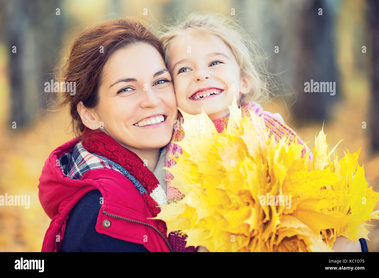 Sourire petite fille et sa mère profiter de promenade en automne parc et jouer avec des feuilles d'automne Banque D'Images