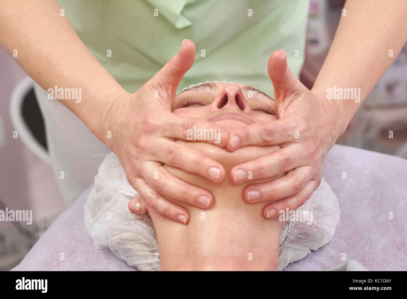Les mains des femmes, d'un cosmétique massage du visage. Banque D'Images