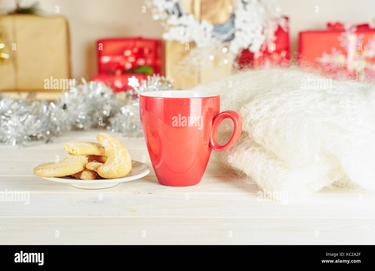 Tasse de café rouge sur la table en bois blanc à côté de cookies et tricots avec les coffrets cadeaux sur l'arrière-plan Banque D'Images