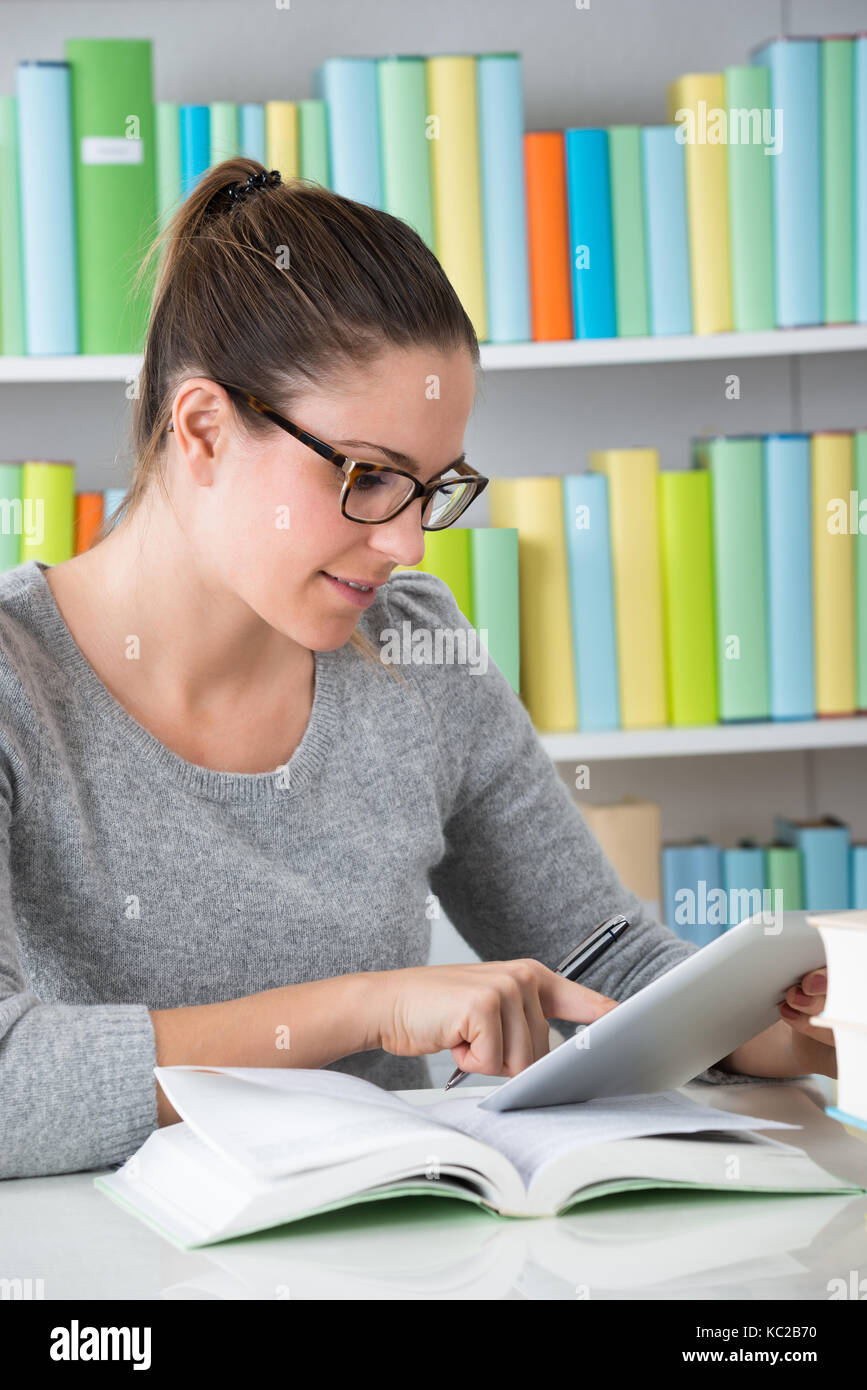 Young Woman Using Digital Tablet In Library Banque D'Images