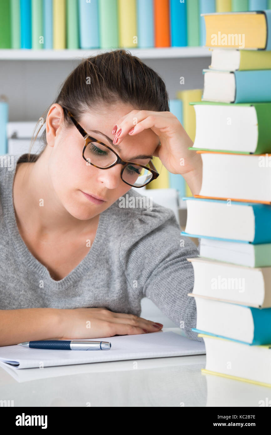 Photo de Jeune femme assise enfoncée dans la bibliothèque Banque D'Images