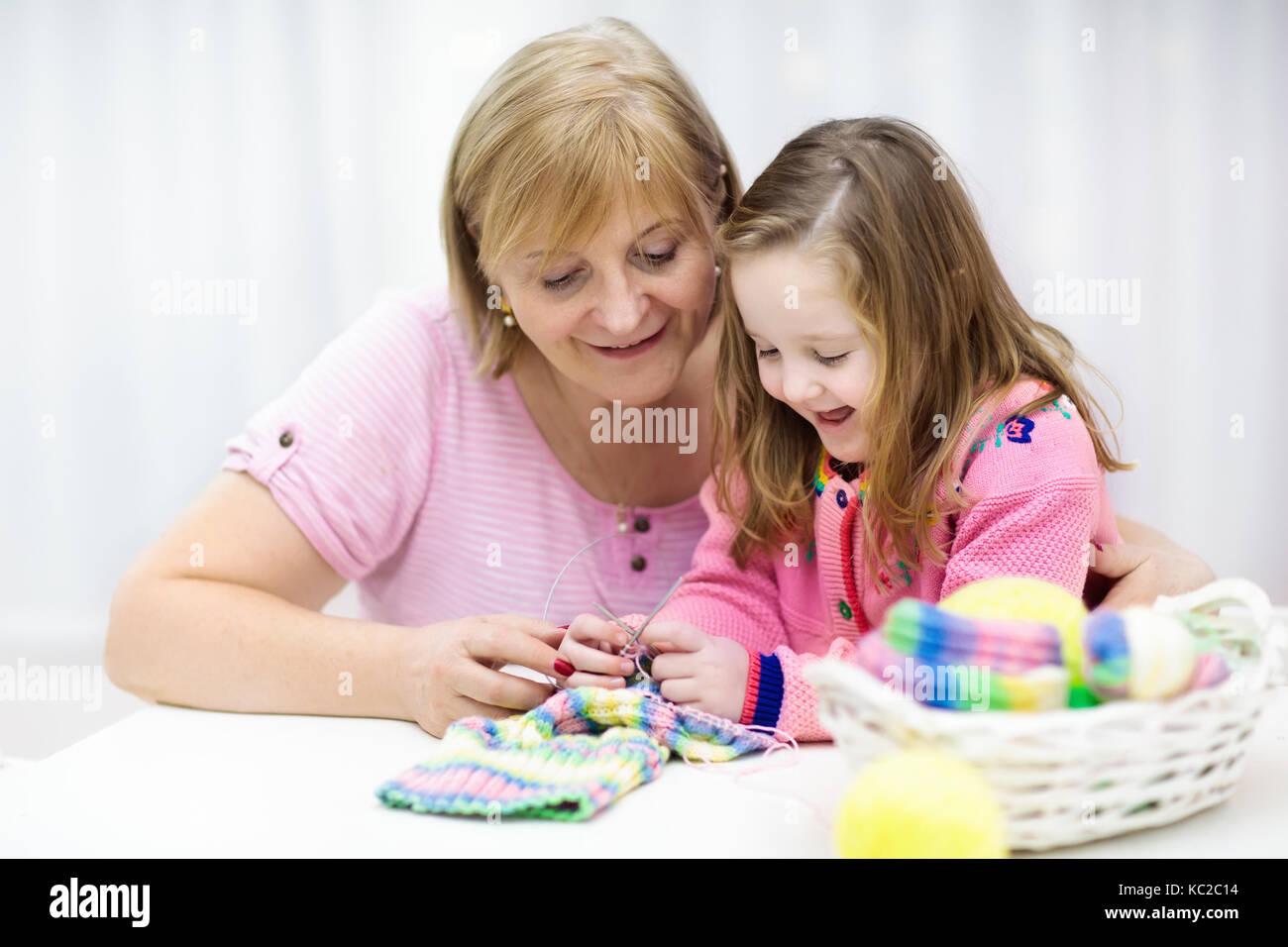 La mère et l'enfant. tricot enseignement maman petite fille à tricoter. L'artisanat pour les enfants. outils de tricot, d'aiguilles et de fils dans le panier de balles en tricot fait main cicatrice. Banque D'Images