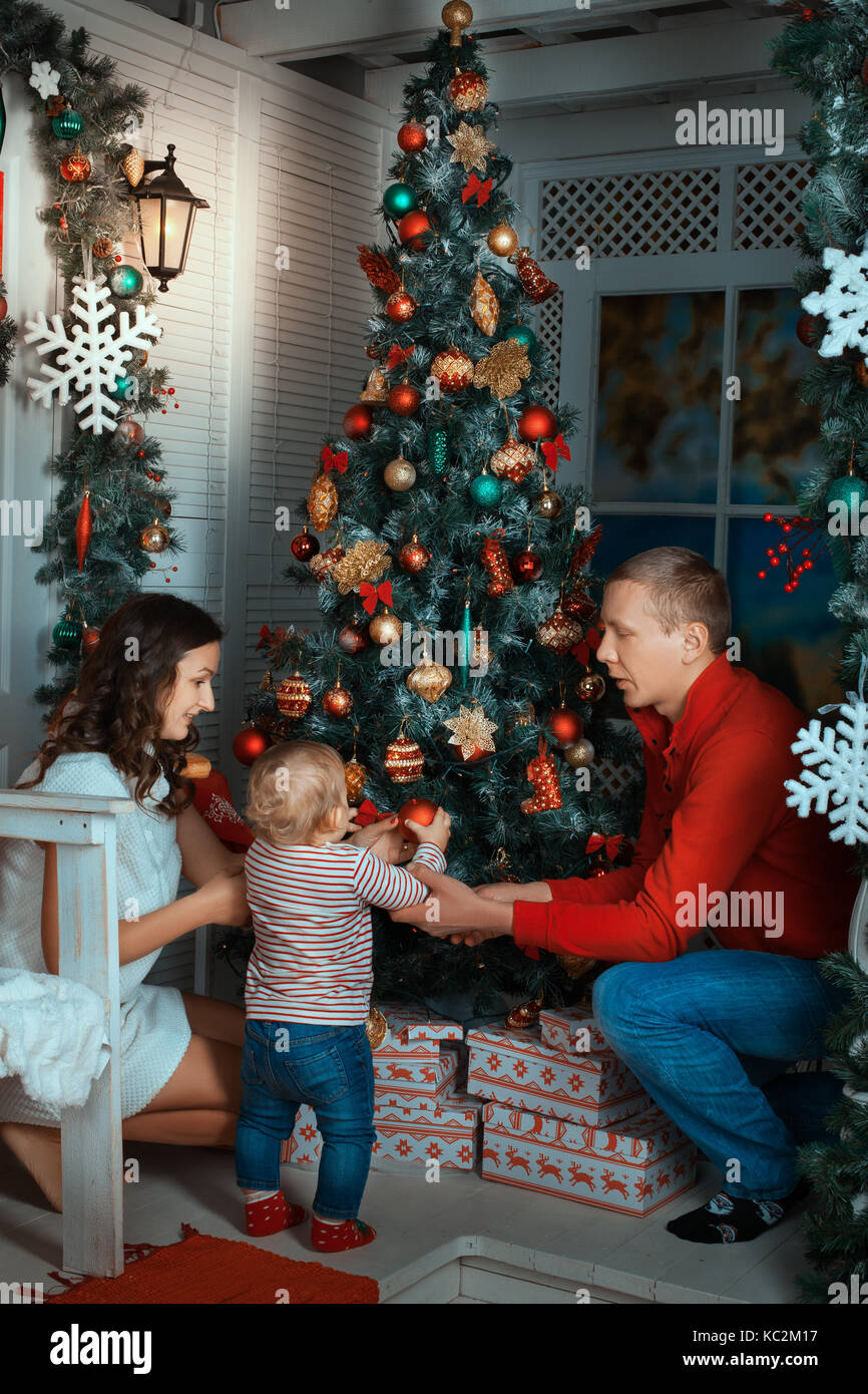 Les parents et l'enfant près d'un arbre de Noël. les parents helping daughter decorating a Christmas Tree Banque D'Images