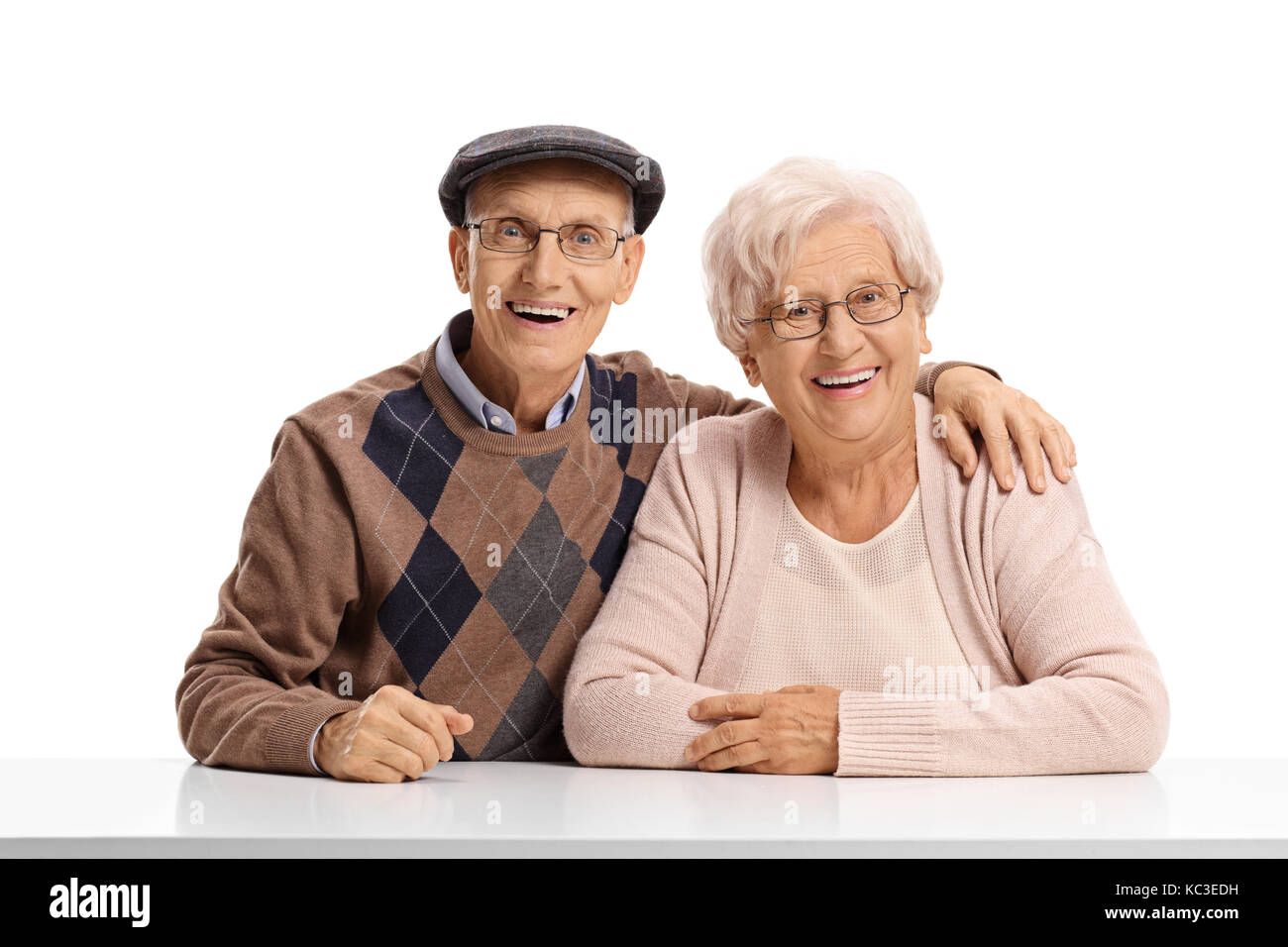 Couple assis à une table, regardant la caméra et smiling isolé sur fond blanc Banque D'Images