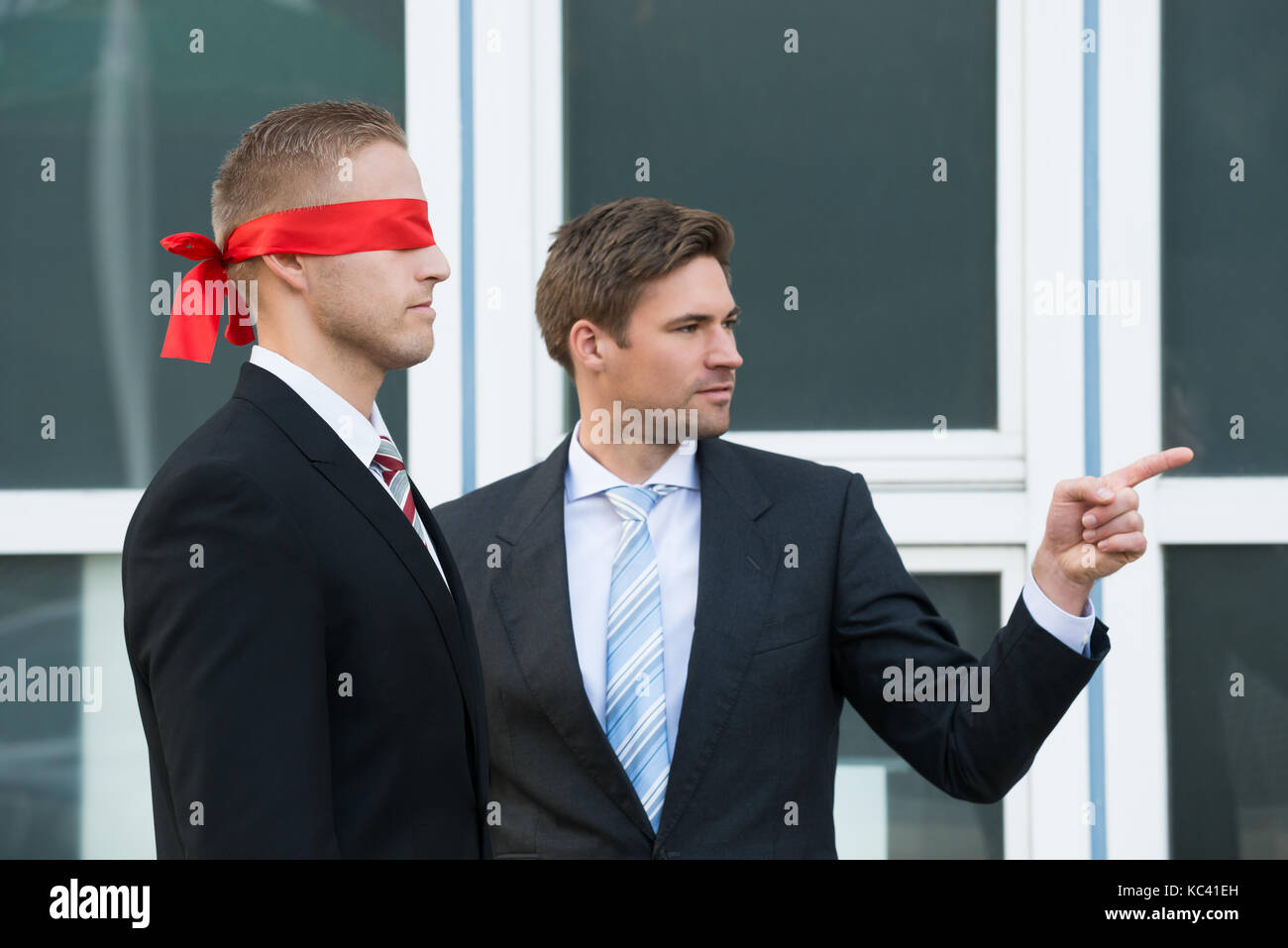 Certain jeune homme d'aider les partenaires à l'extérieur du bureau, les yeux bandés Banque D'Images