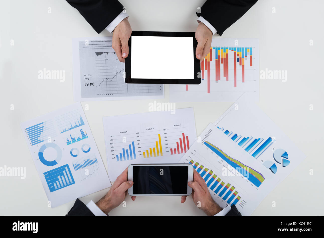 Tourné directement au-dessus des hommes d'affaires à l'aide de tablettes numériques avec des données financières sur la table Banque D'Images