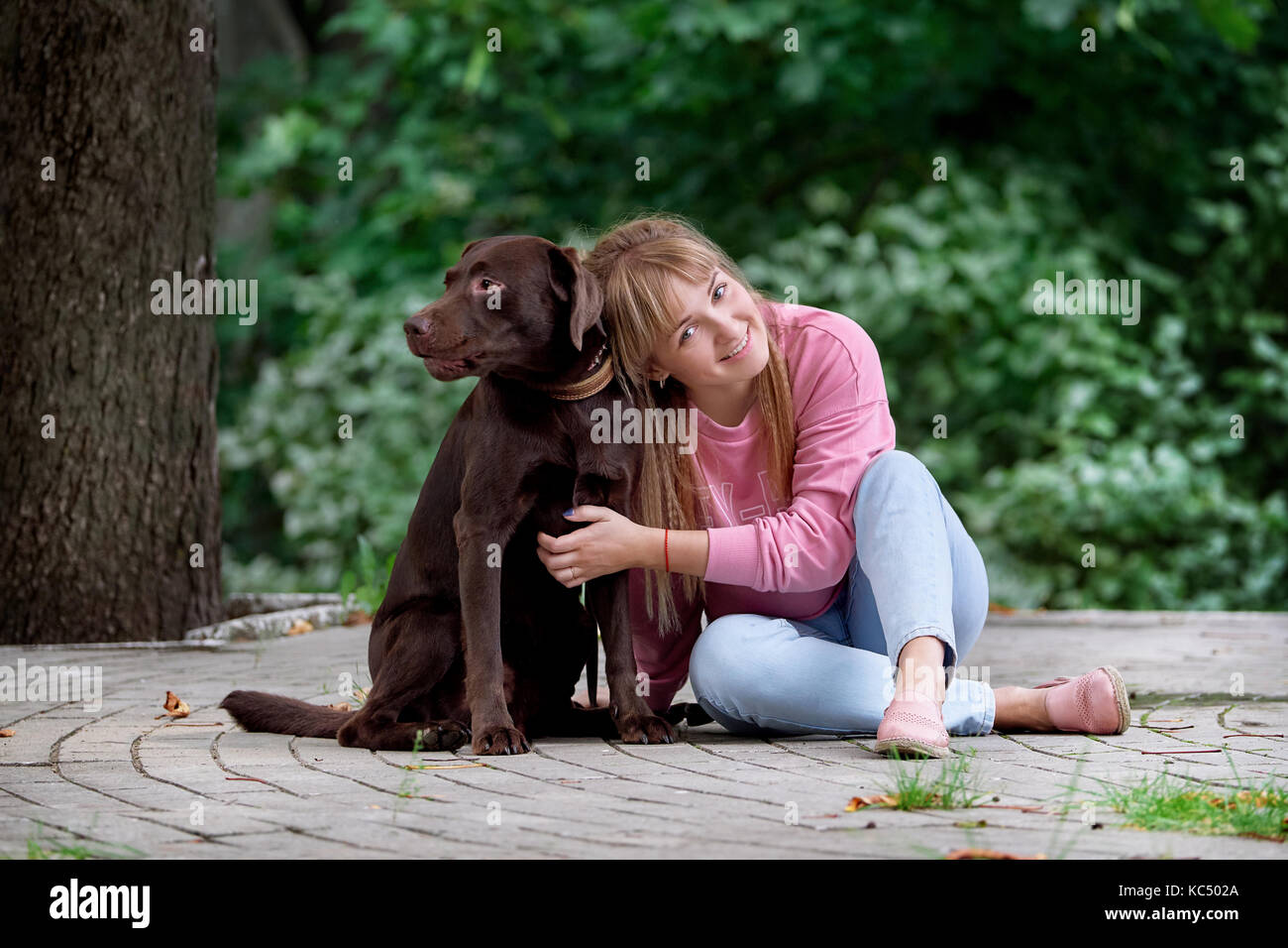 Smiling girl relaxing with dog.labrador assis à côté Banque D'Images