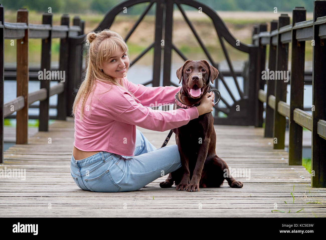 Blonde girl smiling with dog labrador.labrador assis à côté Banque D'Images