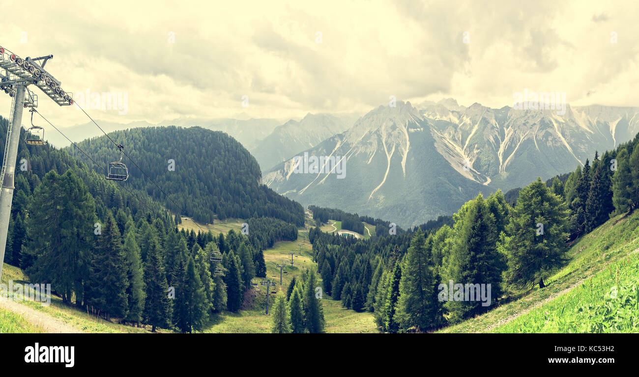 Paysage de montagne avec des forêts, dolomites, valley et télésiège en été. ciel avec nuages. photos avec filtre effet vintage. Banque D'Images