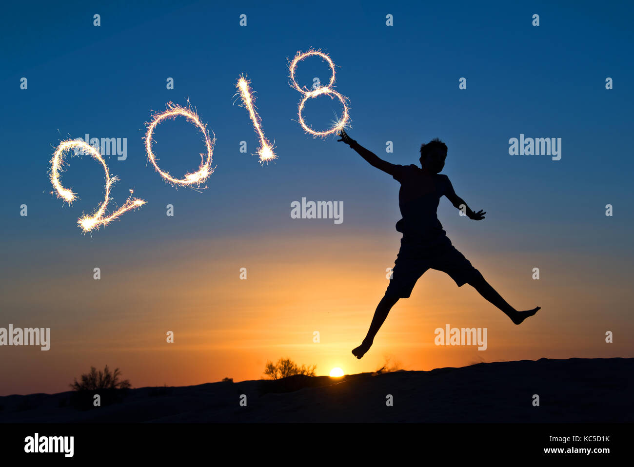 2018 écrit avec sparkles, silhouette d'un garçon sautant dans le soleil Banque D'Images