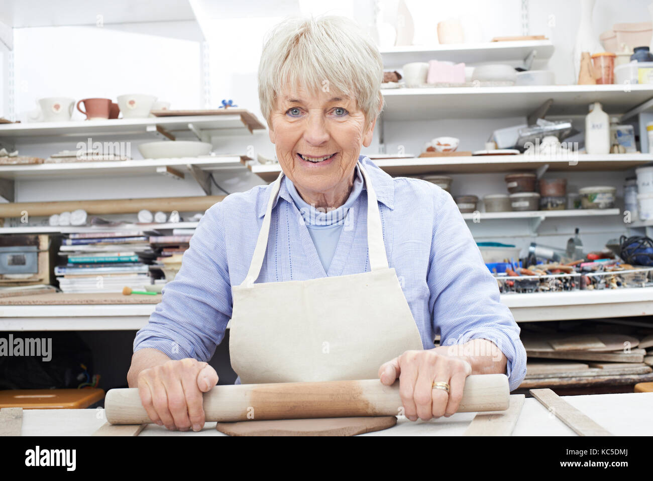 Portrait of senior woman le déploiement d'argile dans un atelier de poterie Banque D'Images