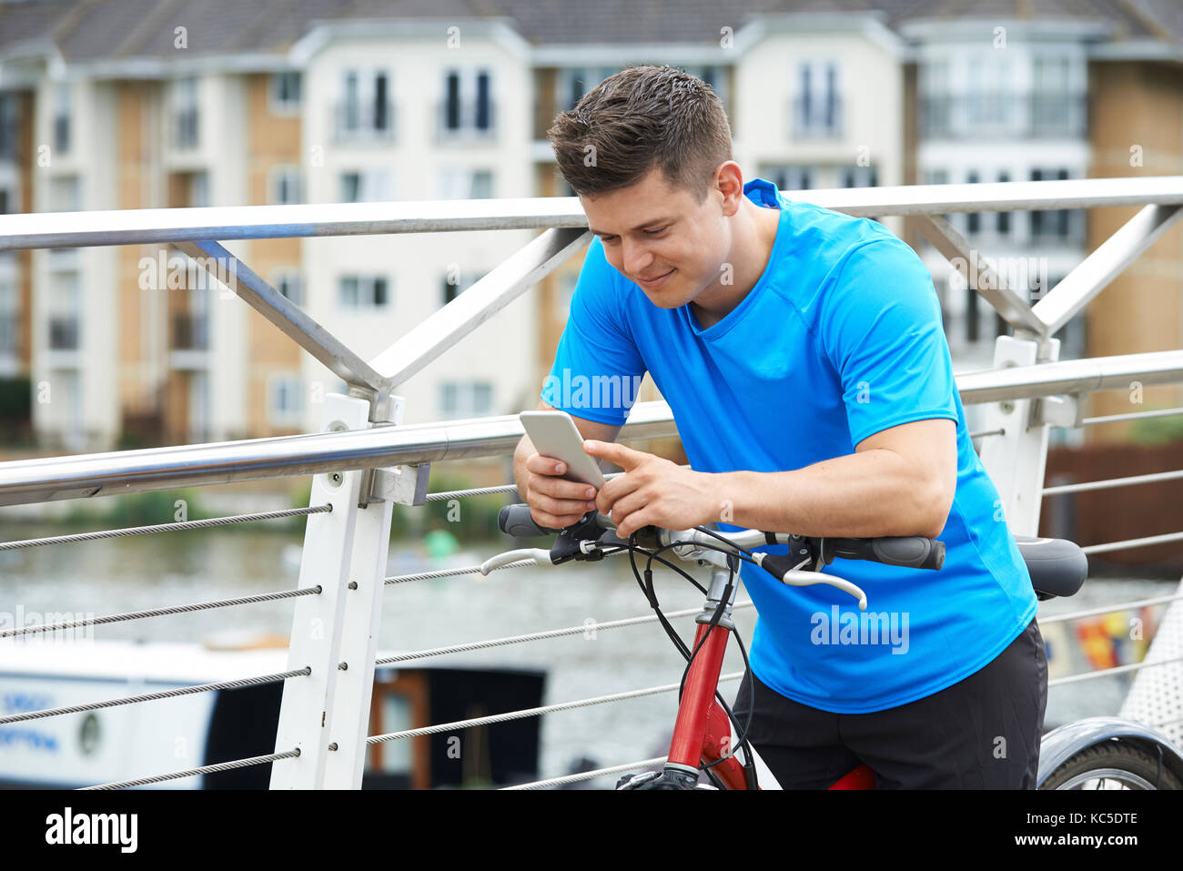 Jeune homme à l'aide de téléphone mobile tandis que dehors sur balade en vélo en milieu urbain Banque D'Images