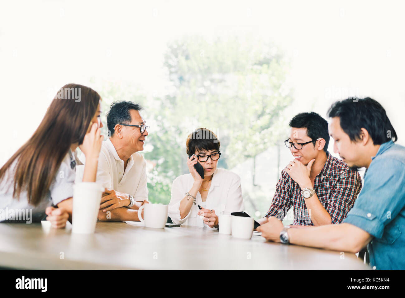 Groupe diversifié de cinq affaires asiatiques en personne à la réunion de l'équipe café ou moderne bureau stratégique. Remue-méninges, propriétaire de petite entreprise, parler de la famille, Banque D'Images