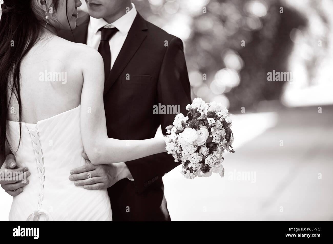Asian wedding couple hugging les uns les autres, se concentrer sur le bouquet, noir et blanc. Banque D'Images
