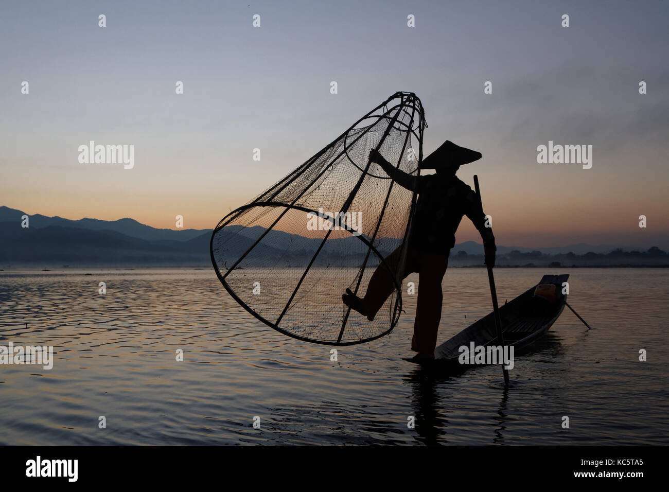E lac dans la lumière du matin. Ces pêcheurs pratiquent un style distinctif de l'aviron, l'emballage une jambe autour de la rame. Banque D'Images