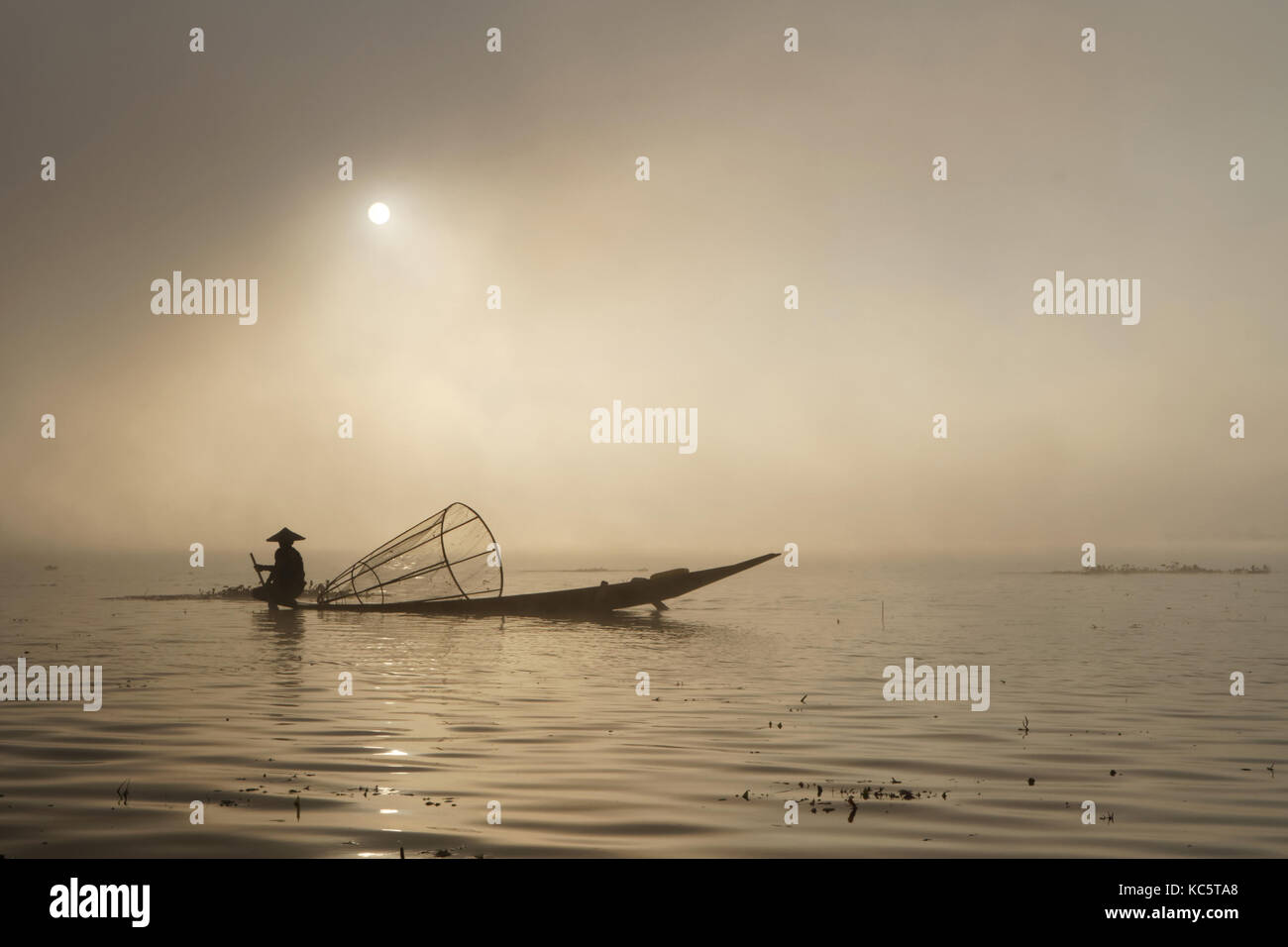 E lac dans la lumière du matin. Ces pêcheurs pratiquent un style distinctif de l'aviron, l'emballage une jambe autour de la rame. Banque D'Images