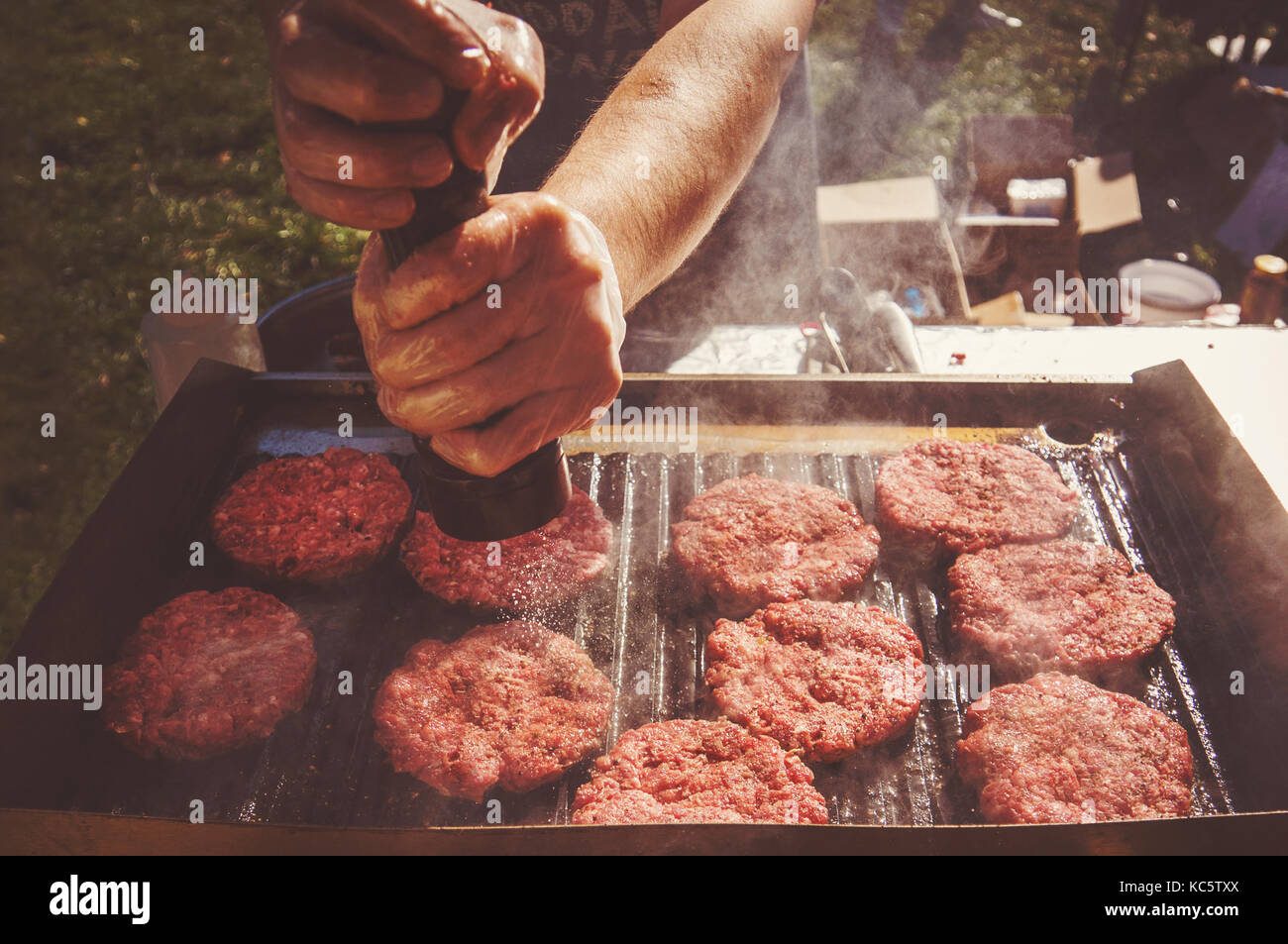 Poivre préparation chef à l'extérieur barbecue burgers. Faire cuire les boulettes frites cornichons frits sur le grill Banque D'Images