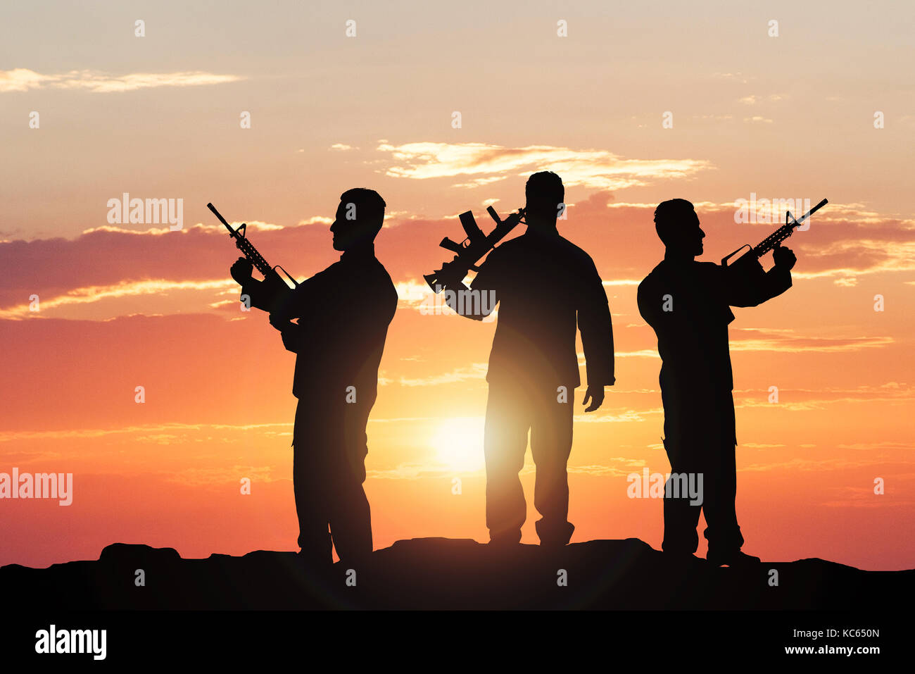 Silhouette de soldats avec des fusils contre ciel dramatique Banque D'Images