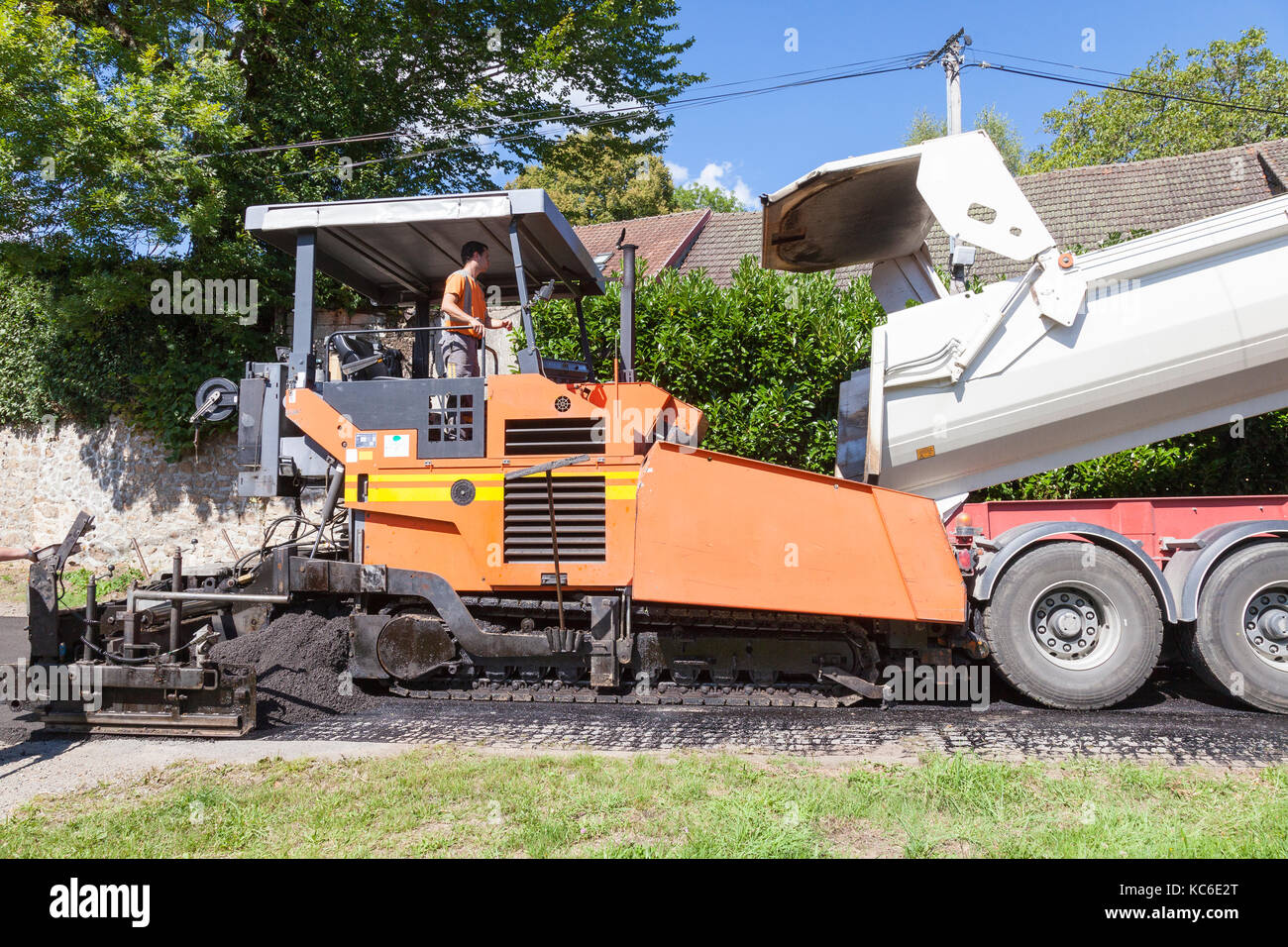 Goudronnage de la route et l'extrémité de la machine chariot étroit un goudronnage rue village rural en intervenant en tandem avec le chariot de la machine de remplissage avec un prémélange Banque D'Images