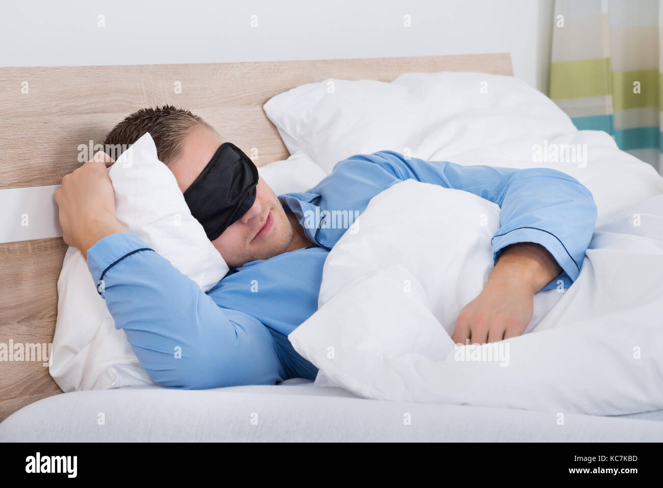 Young man sleeping on lit à l'aide de masque pour les yeux Banque D'Images