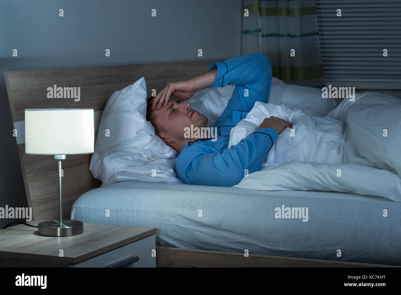 Jeune homme souffrant de maux de tête couché sur lit dans sa chambre à  coucher Photo Stock - Alamy