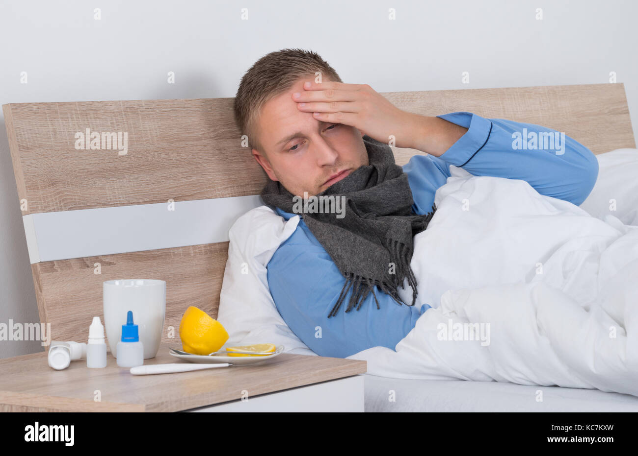 Jeune homme souffrant de maux de tête lying on bed Banque D'Images