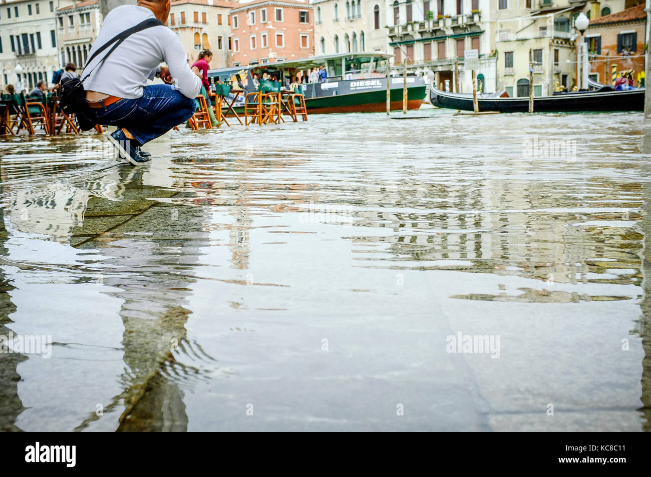 Un photographe s'agenouille pour se faire un bon coup de l'acqua alta, ou l'injection de l'eau élevée, à Venise Banque D'Images