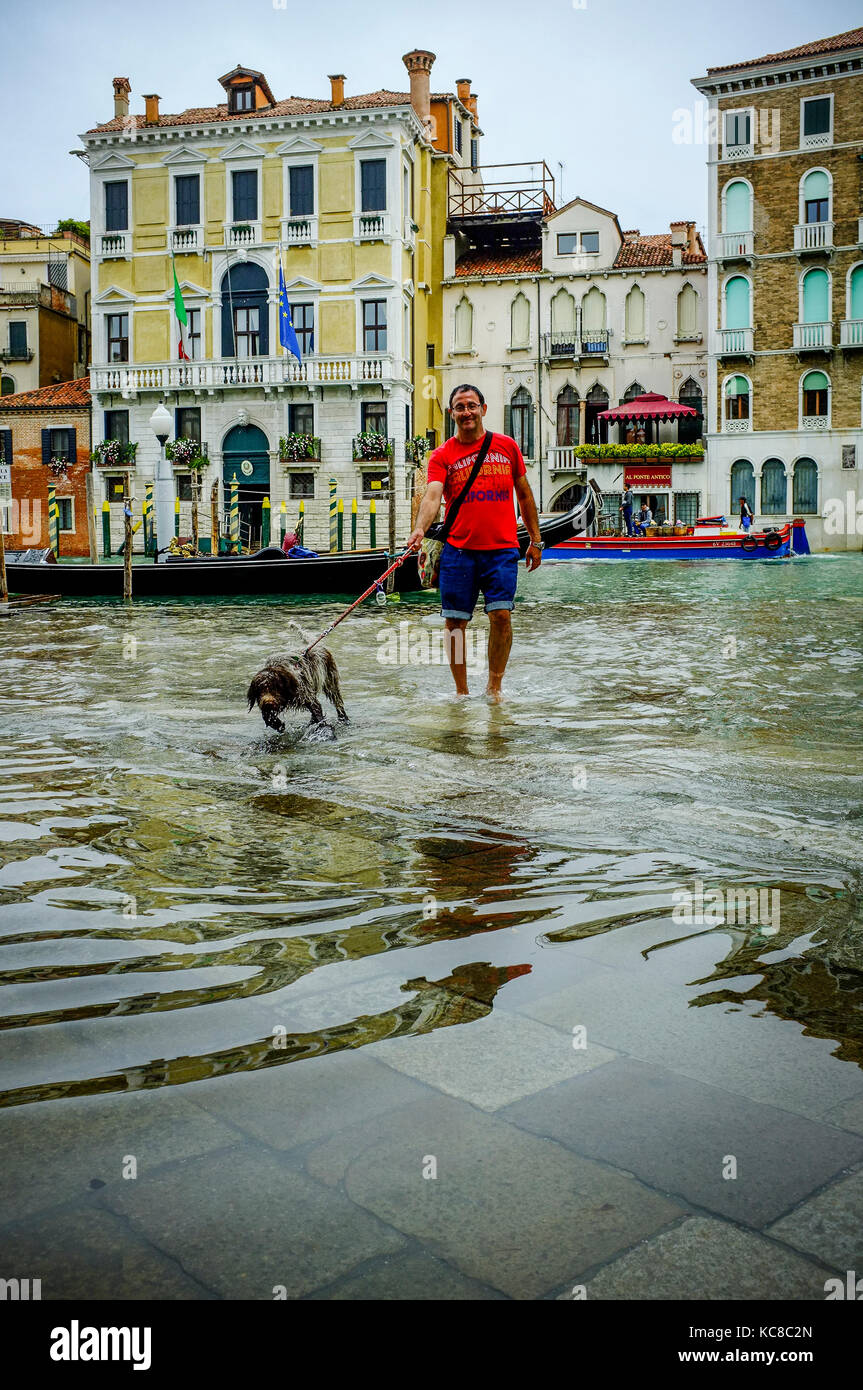 Un homme prend son chien pour une promenade au cours de l'acqua alta, ou l'injection de l'eau élevée, à Venise Banque D'Images
