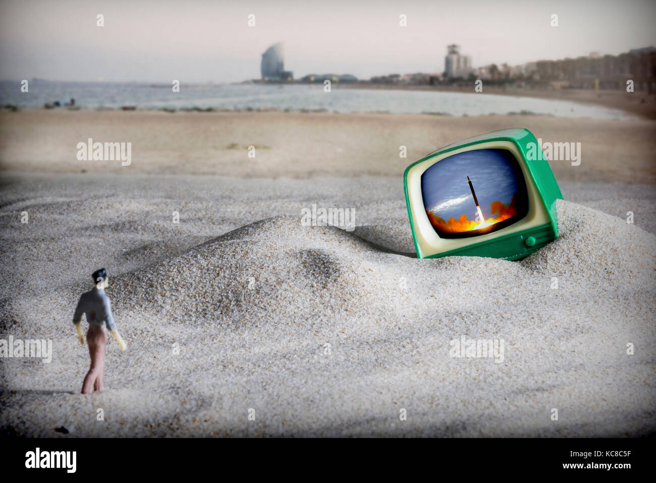 La dramatisation de la fin du monde, un homme marche à une vieille télévision sur la plage de Barcelone, la Corée du Nord vient de lancer un missile balistique t Banque D'Images