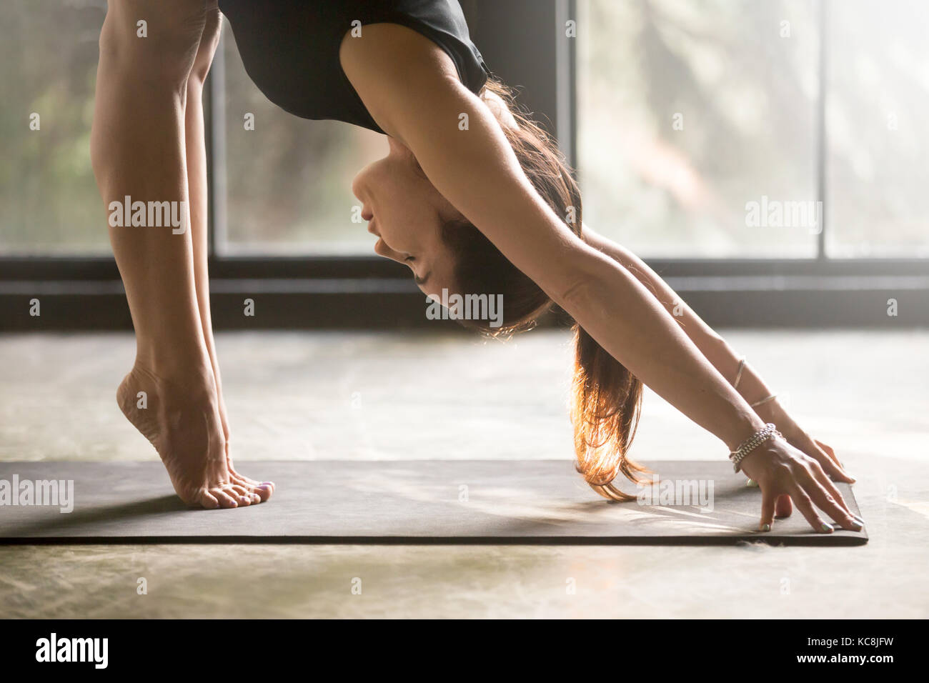 Jeune femme séduisante en uttanasana pose, fond studio Banque D'Images