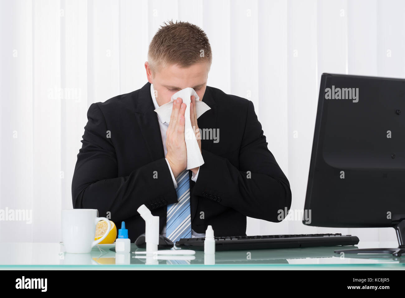 Sick Woman Blowing son nez dans Office avec des médicaments sur 24 Banque D'Images