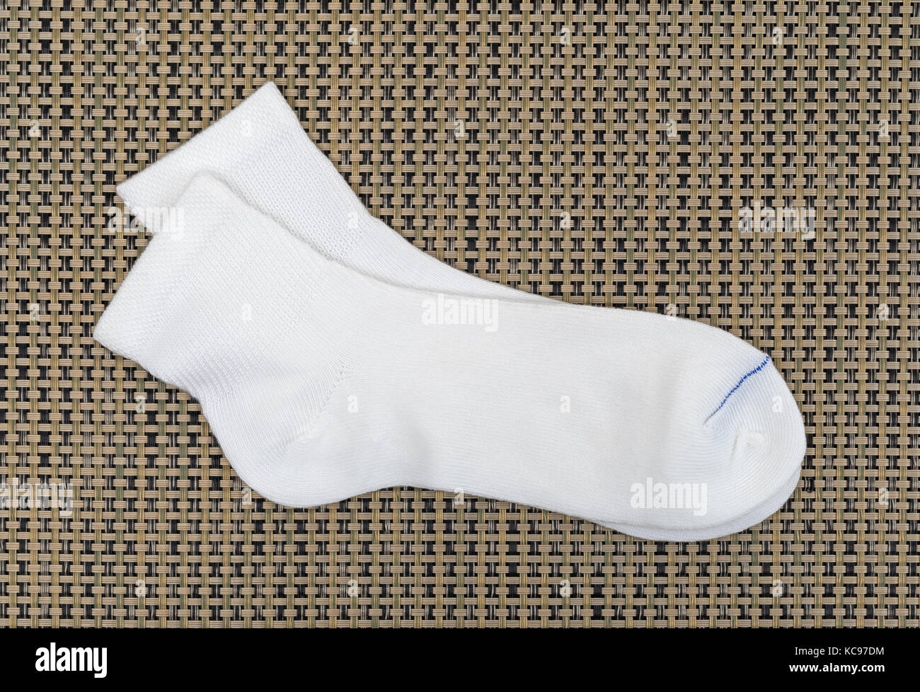 Une seule paire de chaussettes diabétiques sur un tapis tissé. Banque D'Images
