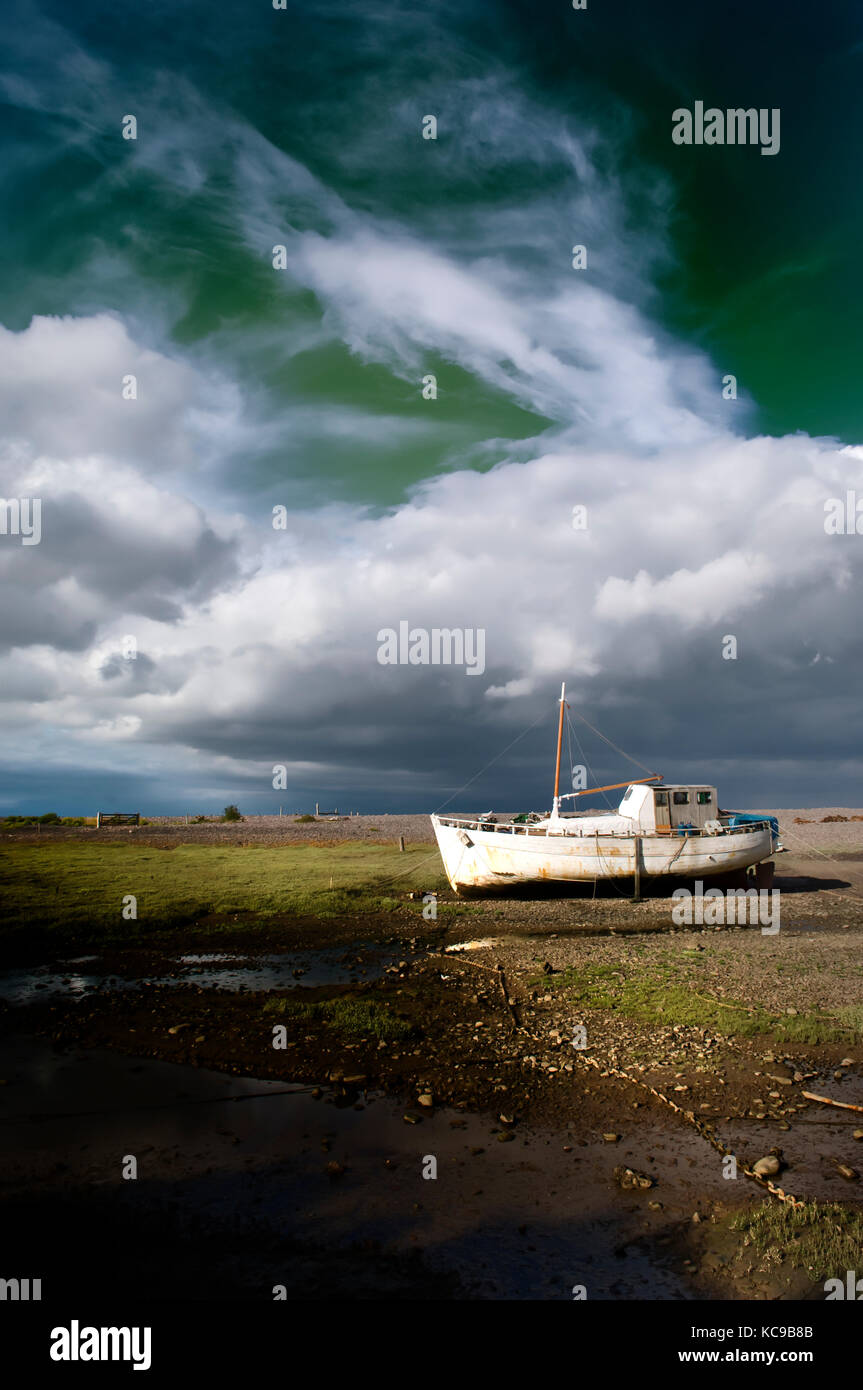 Vieux bateau de pêche sur la vase à marée basse très spectaculaire et sous un ciel d'orage au crépuscule de porlock weir, Somerset, Royaume-Uni. isolement, fantomatique, livre-couverture Banque D'Images